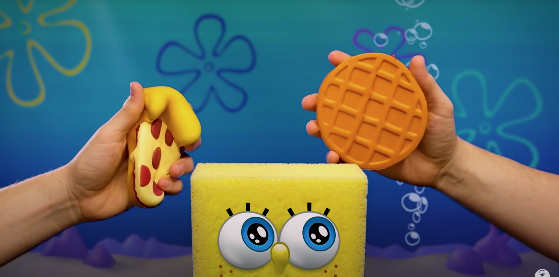 An animated SpongeBob SquarePants surrounded by two human arms and hands with each one squeezing a rubber toy.